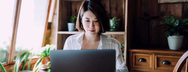 Woman working on her laptop in a home office full of plants