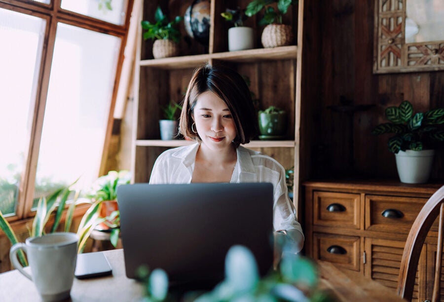 Woman working on her laptop in a home office full of plants