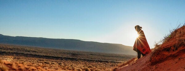 Shadowy figure walking across the Arizona landscape with the sun behind them