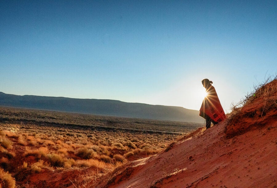 Shadowy figure walking across the Arizona landscape with the sun behind them
