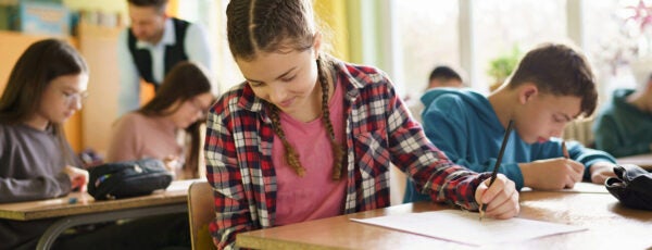 Teenage girl using a smart phone during an exam in the classroom