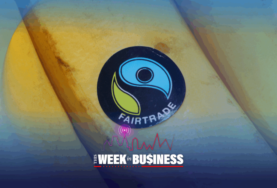 Fairtrade sticker on a banana with graphics for "This Week in Business" at the bottom, including a cityscape and signal icon.