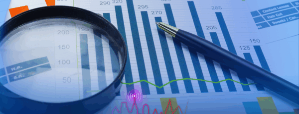Charts and graphs with a pen and magnifying glass, representing business analysis or financial review. The text 